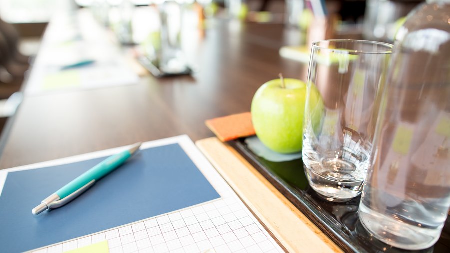 Konferenztisch mit 2 Wassergläsern, Apfel und Block 