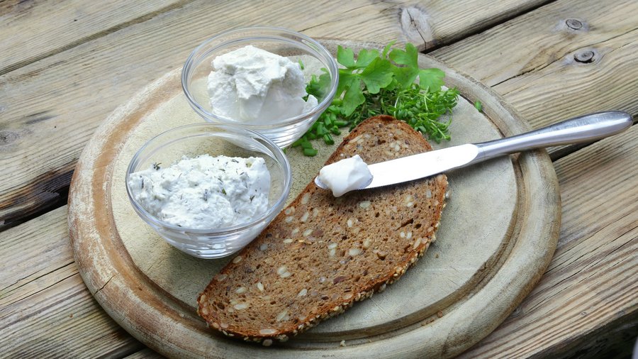 Frischkäse auf Lupinenbasis angerichtet auf einem Holzbrett mit einer Mehrkornbrotscheibe © Fraunhofer IVV  