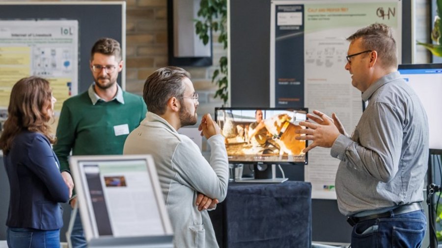 Mehrere Personen stehen in einem Raum vor Postern und Ausstellungsmaterialien und unterhalten sich © EurA AG