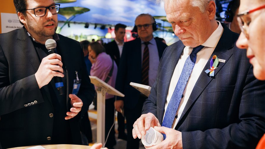 Max Sturm (HS Albstadt-Sigmaringen) erläutert Bundeslandwirtschaftsminister Rainer und Präsidentin Margareta Büning-Fesel (BLE) die innovative Lebensmittelverpackung