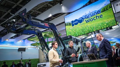 Bundeskanzler Merz und Bundeslandwirtschaftsminister Rainer im Gespräch mit den Entwicklern des FlexETractors Christian Hornung (ONOX) und Julius Wendling (TUM) (v.r.n.l.)